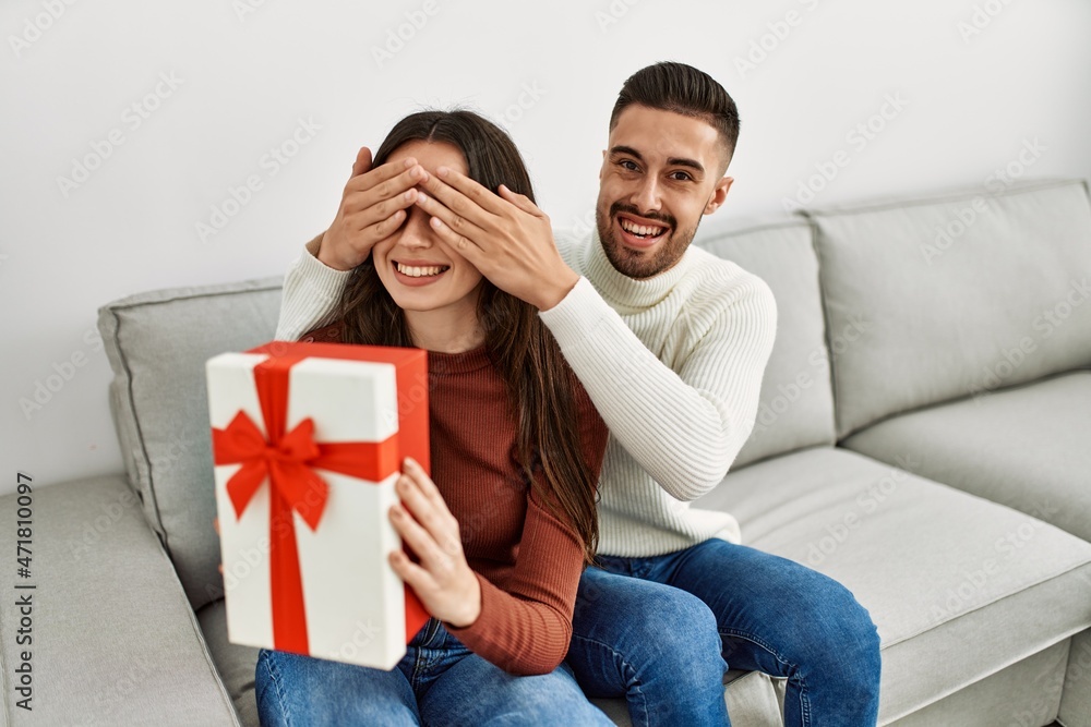 Young hispanic couple smiling happy surprising with birthday gift at home. Young hispanic couple smiling happy surprising with birthday gift at home.