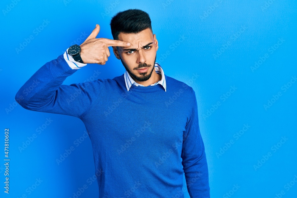 Young hispanic man with beard wearing casual blue sweater pointing unhappy to pimple on forehead, ugly infection of blackhead. acne and skin problem Young hispanic man with beard wearing casual blue sweater pointing unhappy to pimple on forehead, ugly infection of blackhead. acne and skin problem