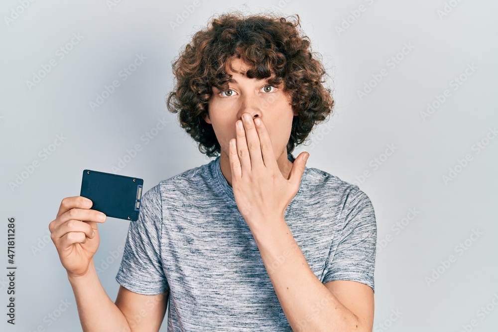 Fotka „Handsome young man holding ssd memory covering mouth with hand,  shocked and afraid for mistake. surprised expression“ ze služby Stock |  Adobe Stock