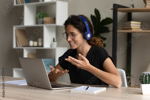 Tableau sur toile Confident hispanic female interpreter work from home office sit at desk in headset talk look on laptop screen translate online event