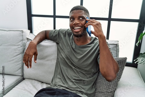 Young african american man smiling confident talking on the smartphone at home