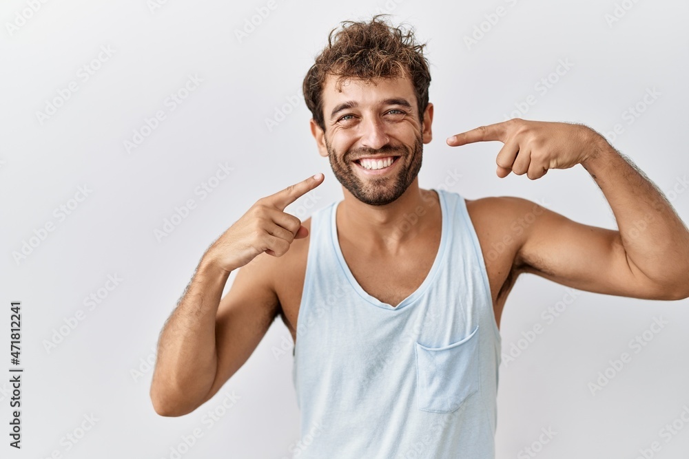 Young handsome man standing over isolated background smiling cheerful showing and pointing with fingers teeth and mouth. dental health concept. Young handsome man standing over isolated background smiling cheerful showing and pointing with fingers teeth and mouth. dental health concept.