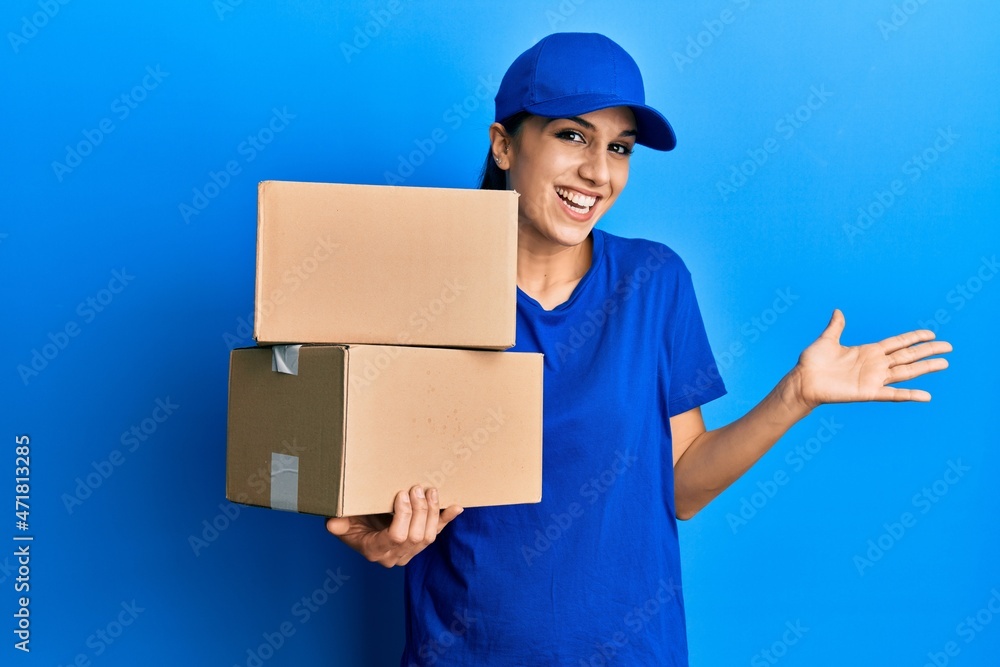Young hispanic woman holding delivery package celebrating achievement with happy smile and winner expression with raised hand Young hispanic woman holding delivery package celebrating achievement with happy smile and winner expression with raised hand
