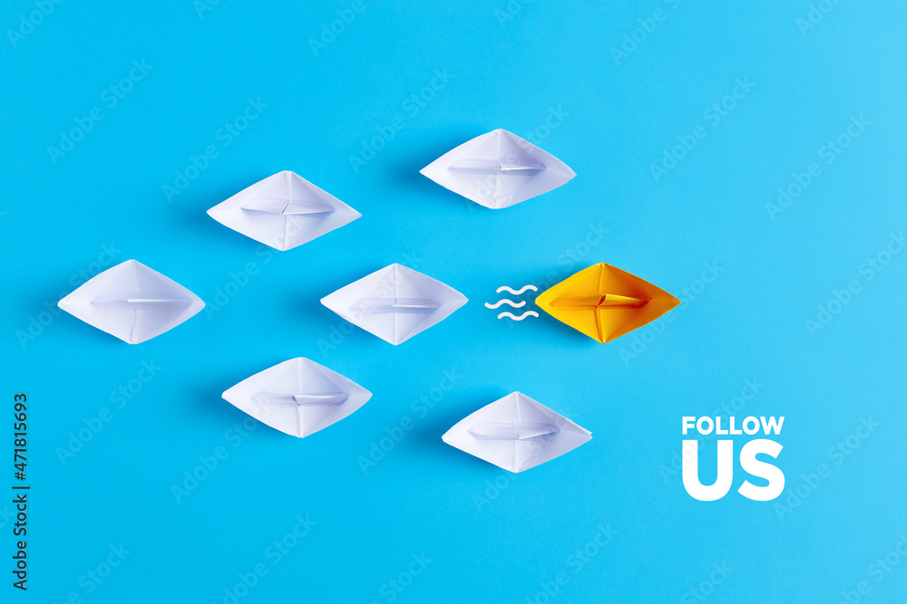 Yellow paper boat leads white paper ships with the follow us message. Social media or internet followers concept. - obrazy, fototapety, plakaty 