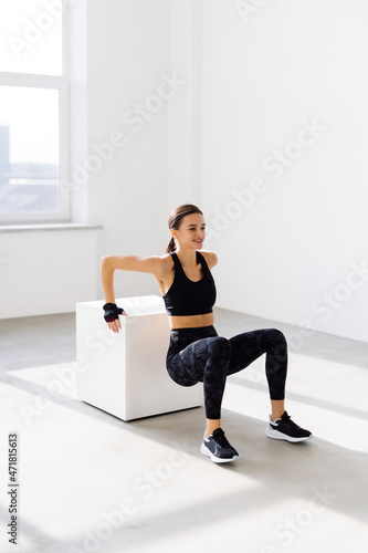 Fototapeta Naklejka Na Ścianę i Meble -  Young fit woman doing a box jump exercise. Muscular woman doing a box squat at the gym