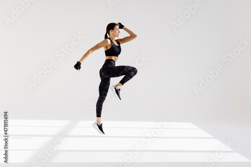 Attractive excited fitness woman in sportwear jumping of joy isolated over white background