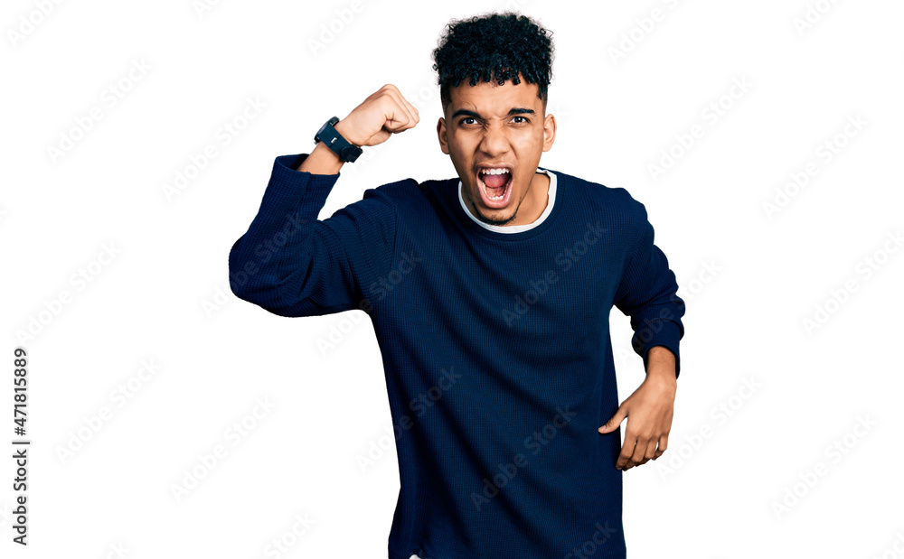 Young african american man wearing casual clothes angry and mad raising fist frustrated and furious while shouting with anger. rage and aggressive concept. Young african american man wearing casual clothes angry and mad raising fist frustrated and furious while shouting with anger. rage and aggressive concept.