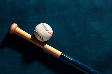 Blue wooden baseball bat and a baseball ball on blue background