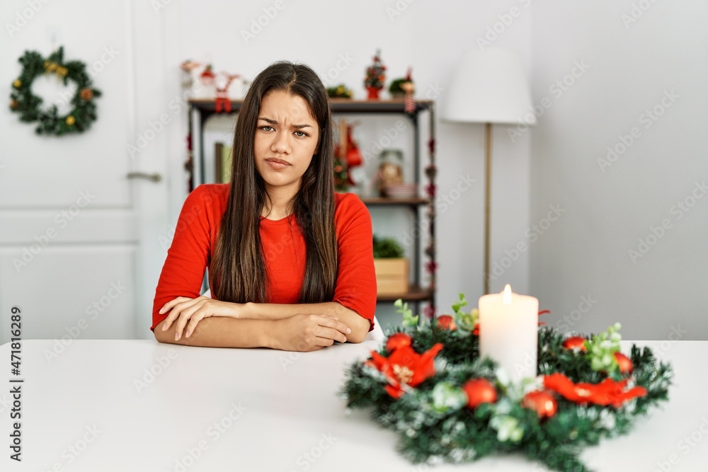 Young brunette woman sitting on the table on christmas skeptic and nervous, disapproving expression on face with crossed arms. negative person. Young brunette woman sitting on the table on christmas skeptic and nervous, disapproving expression on face with crossed arms. negative person.