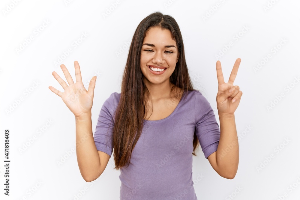 Young brunette woman standing by isolated background showing and pointing up with fingers number seven while smiling confident and happy. Young brunette woman standing by isolated background showing and pointing up with fingers number seven while smiling confident and happy.
