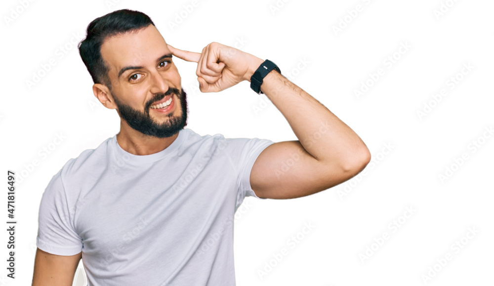 Naklejka premium Young man with beard wearing casual white t shirt smiling pointing to head with one finger, great idea or thought, good memory