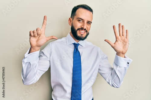 Young man with beard wearing business tie showing and pointing up with fingers number seven while smiling confident and happy.
