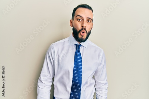 Young man with beard wearing business tie afraid and shocked with surprise expression, fear and excited face.