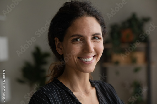 Portrait of smiling motivated young latin woman student worker attractive brunette with beautiful white smile long curly hair done back in bun. Pretty face of happy optimistic casual millennial female