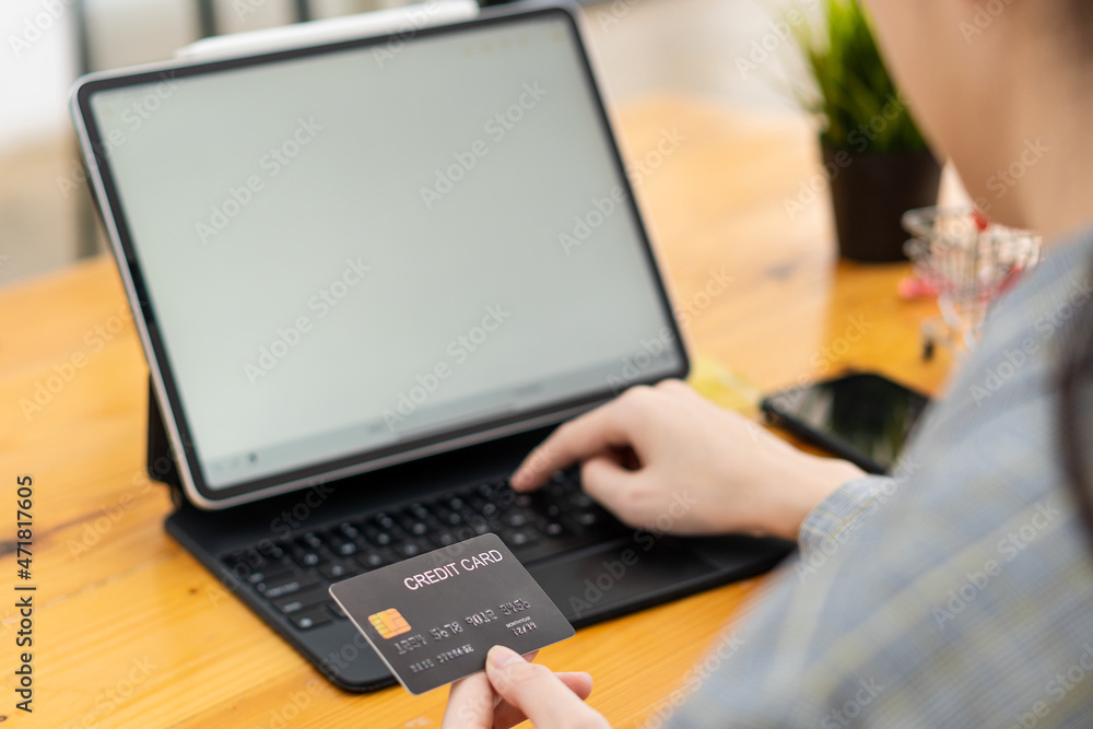 woman holding credit card and using laptop at home Businessman or entrepreneur working online shopping e-commerce internet banking spend money women work at home concept using credit card woman holding credit card and using laptop at home Businessman or entrepreneur working online shopping e-commerce internet banking spend money women work at home concept using credit card