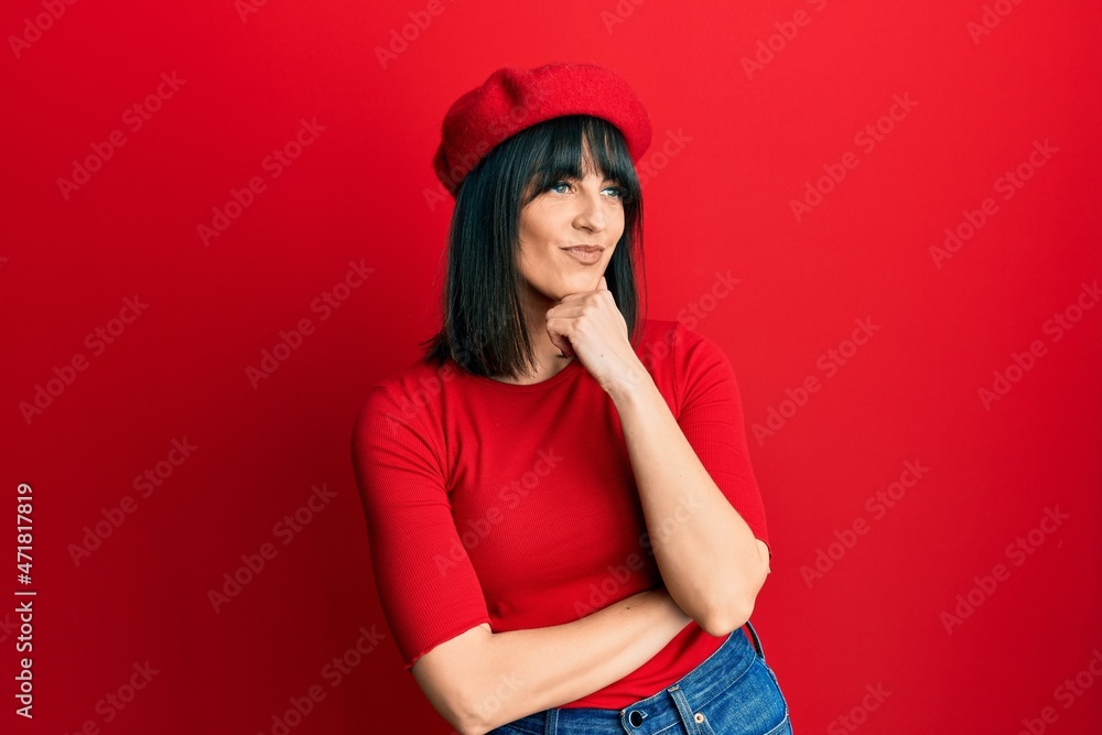 Young hispanic woman wearing french look with beret with hand on chin thinking about question, pensive expression. smiling with thoughtful face. doubt concept. Young hispanic woman wearing french look with beret with hand on chin thinking about question, pensive expression. smiling with thoughtful face. doubt concept.