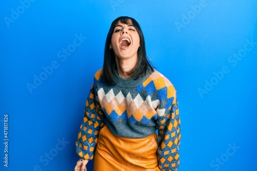 Young hispanic woman wearing casual winter sweater winking looking at the camera with sexy expression  cheerful and happy face.