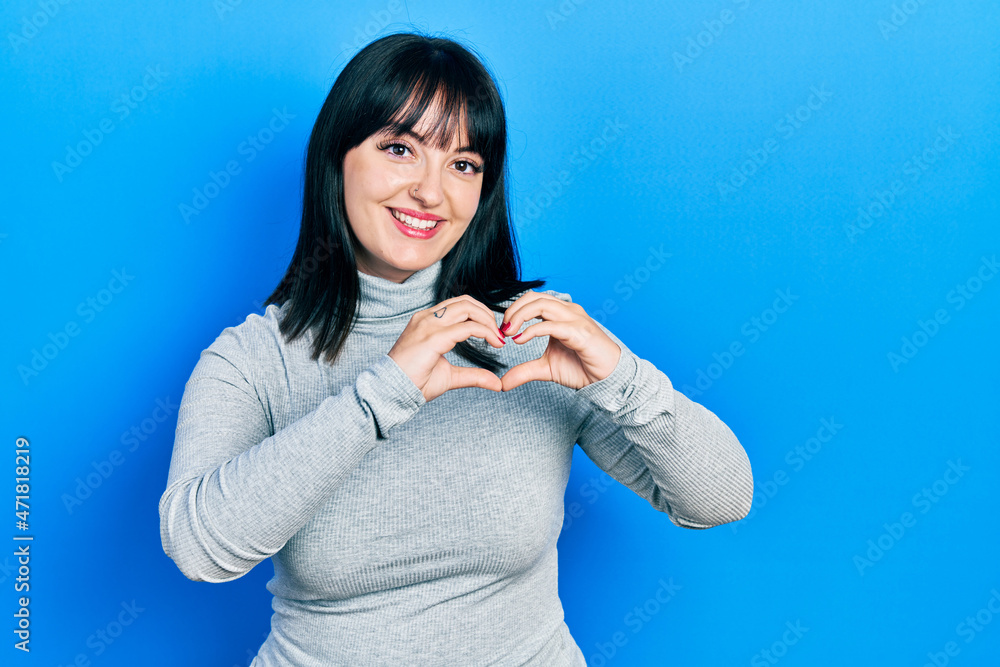 Young hispanic woman wearing casual clothes smiling in love doing heart symbol shape with hands. romantic concept. Young hispanic woman wearing casual clothes smiling in love doing heart symbol shape with hands. romantic concept.