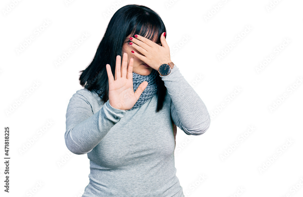 Young hispanic plus size woman wearing winter scarf covering eyes with hands and doing stop gesture with sad and fear expression. embarrassed and negative concept. Young hispanic plus size woman wearing winter scarf covering eyes with hands and doing stop gesture with sad and fear expression. embarrassed and negative concept.