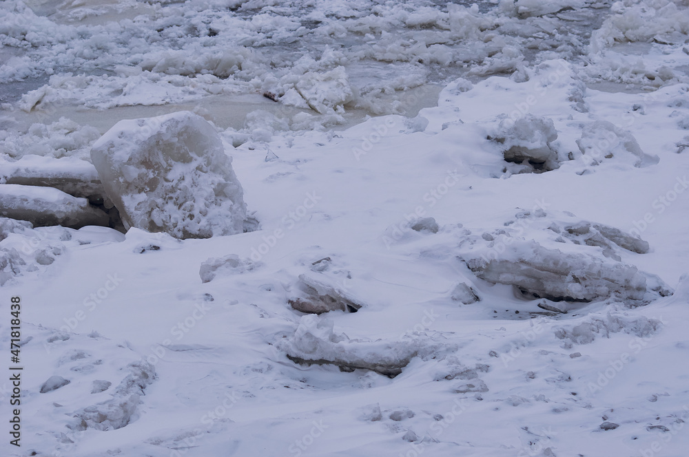 Snow-covered ice on the river during a snowfall. Winter texture. Suga and ice floes. Ice blocks.