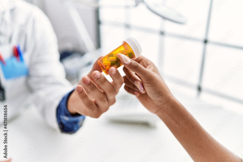 Man and woman wearing doctor uniform having medical consultation prescribe pills at clinic Man and woman wearing doctor uniform having medical consultation prescribe pills at clinic