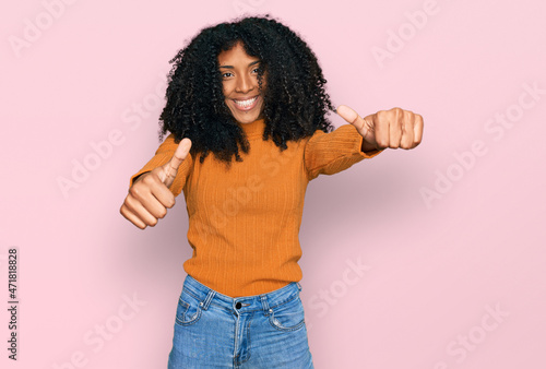 Young african american girl wearing casual clothes approving doing positive gesture with hand, thumbs up smiling and happy for success. winner gesture.