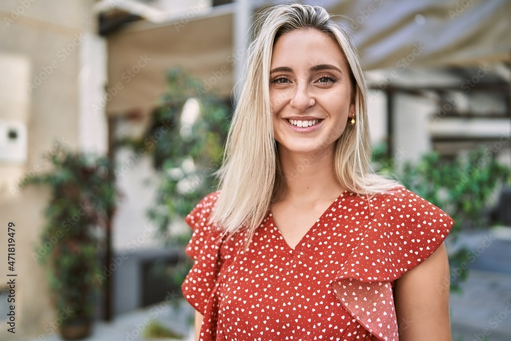 Young blonde girl smiling happy standing at the city.