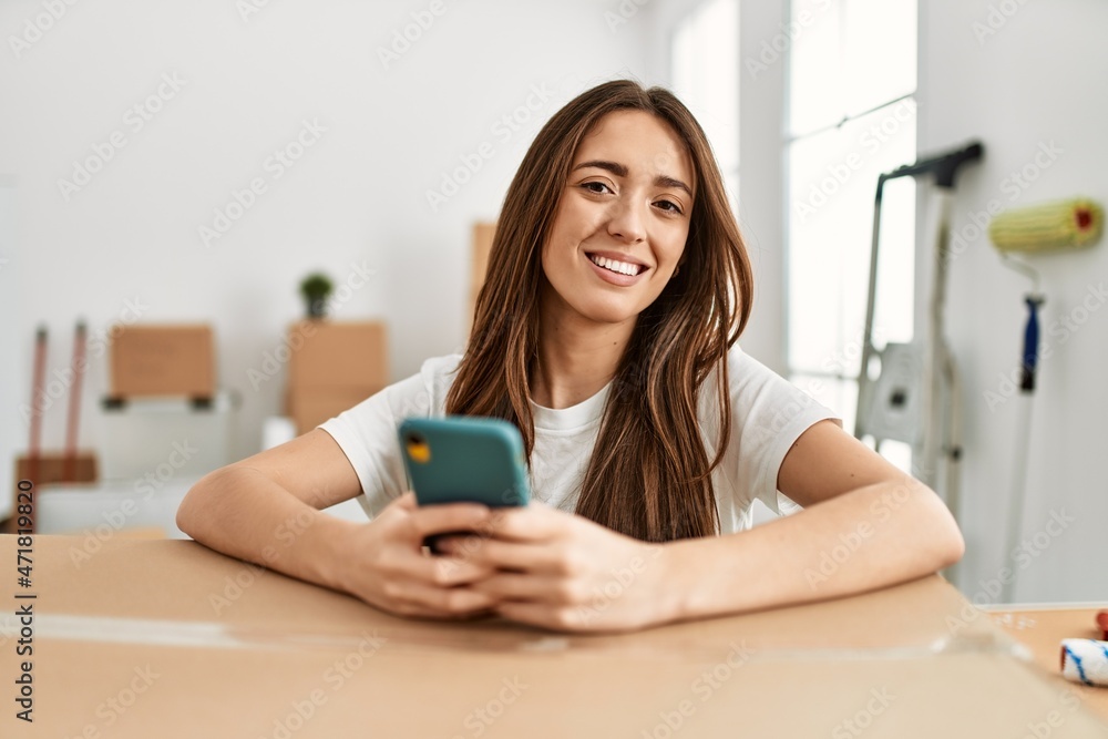 Young hispanic woman smiling confident using smartphone at new home Young hispanic woman smiling confident using smartphone at new home