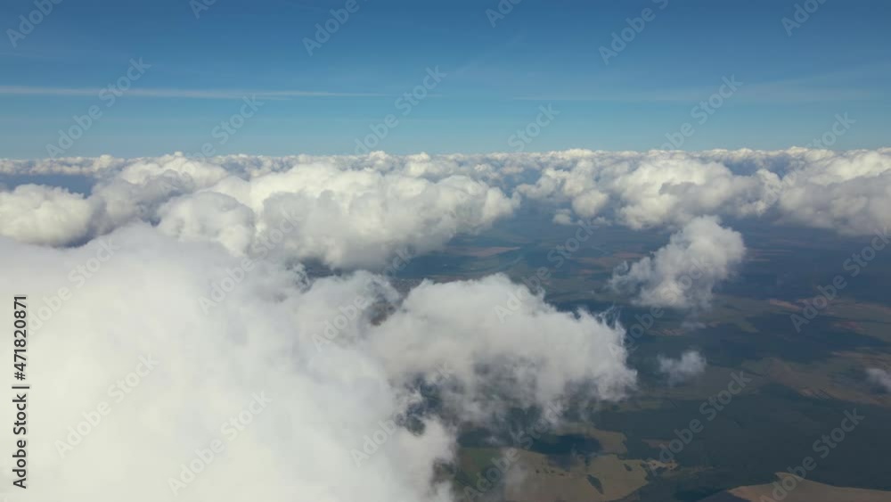 Aerial view from airplane window at high altitude of earth covered with white puffy cumulus clouds Aerial view from airplane window at high altitude of earth covered with white puffy cumulus clouds