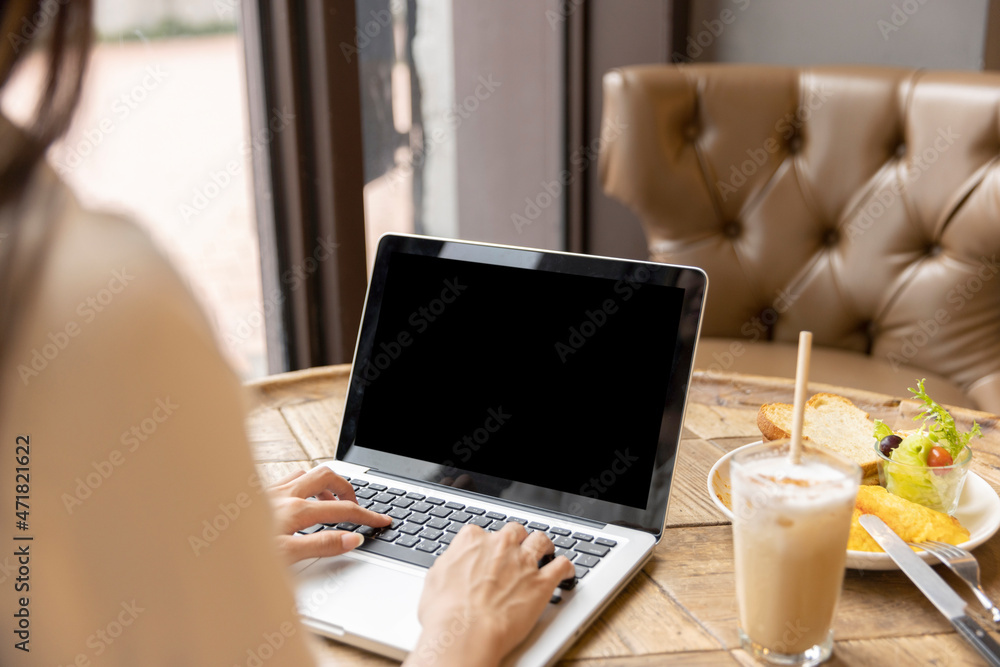 Woman's hand using and touching on laptop with blank desktop screen in coffee shop Woman's hand using and touching on laptop with blank desktop screen in coffee shop