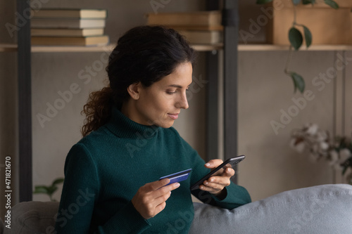 Online transaction. Focused young latina female making easy safe cashless payment at mobile bank application. Attentive hispanic woman pay for purchases at internet shop using debit card. Copyspace photo