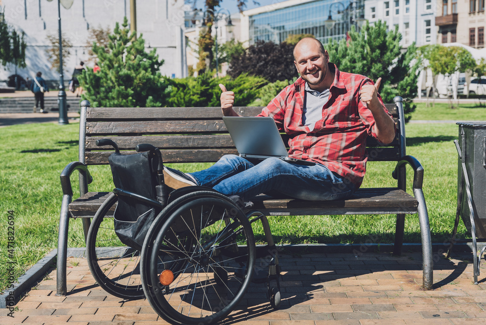 Freelancer with a physical disability in a wheelchair working at the park Freelancer with a physical disability in a wheelchair working at the park