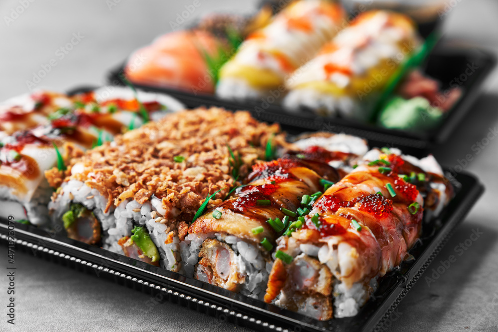 Delivery tray of uramaki sushi on a concrete surface Delivery tray of uramaki sushi on a concrete surface