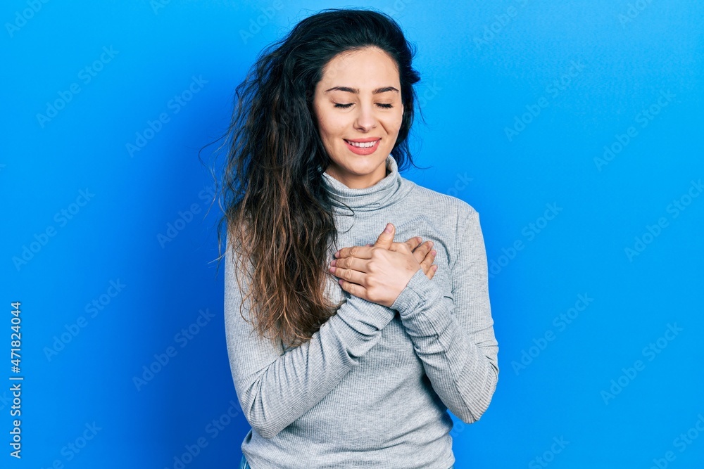 Young hispanic woman wearing casual clothes smiling with hands on chest with closed eyes and grateful gesture on face. health concept. Young hispanic woman wearing casual clothes smiling with hands on chest with closed eyes and grateful gesture on face. health concept.