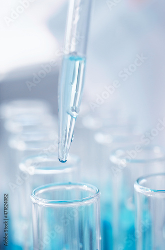 A drop from a laboratory pipette falls into a flask, close-up. Scientific laboratory research. Antiviral vaccine development.