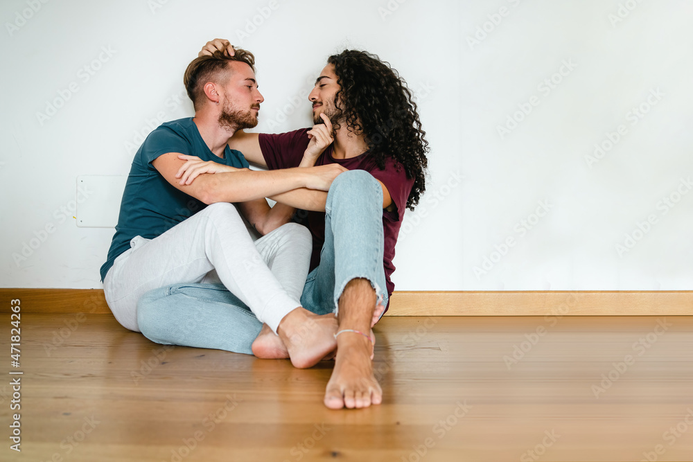 Romantic gay boyfriends sitting on the floor tenderly caressing each other. LGBT concept. Romantic gay boyfriends sitting on the floor tenderly caressing each other. LGBT concept.