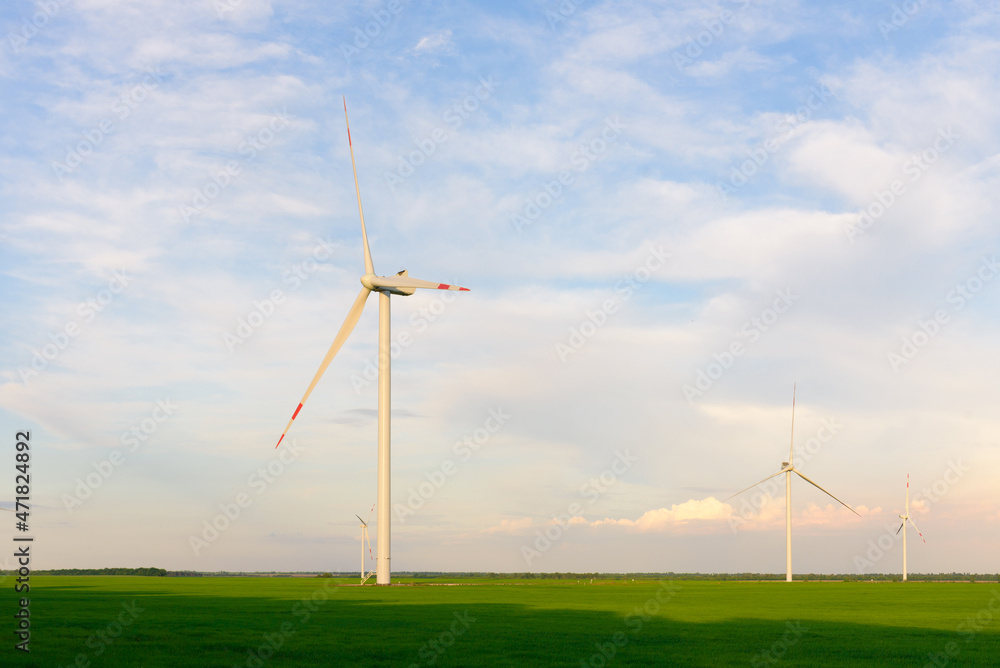 View on alternative energy windmills in a windpark in Ulyanovsk in front of a blue sky. Windmills for electric power production. View on alternative energy windmills in a windpark in Ulyanovsk in front of a blue sky. Windmills for electric power production.