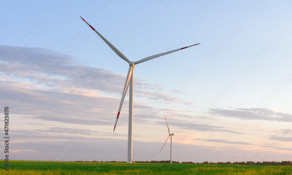 View on alternative energy windmills in a windpark in Ulyanovsk in front of a blue sky. Windmills for electric power production. View on alternative energy windmills in a windpark in Ulyanovsk in front of a blue sky. Windmills for electric power production.