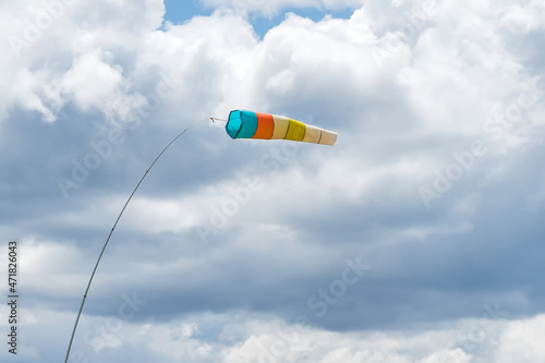 Wind sock. Wind designator against the blue cloudy sky. Wind sleeve flying close up.