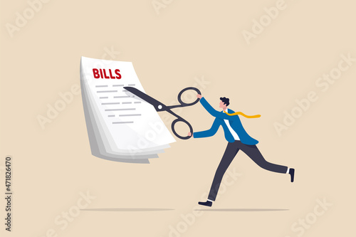 Cut bills to reduce cost and expense, tax or payment deduction, limit spending or control cash flow concept, businessman using big scissors to cut pile of bills and expense.