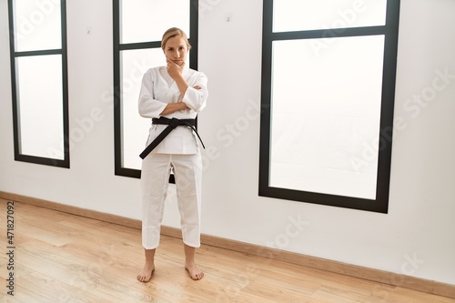 Caucasian young blonde woman wearing karate kimono and black belt thinking looking tired and bored with depression problems with crossed arms.