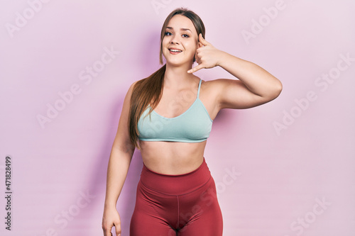 Young hispanic girl wearing sportswear smiling doing phone gesture with hand and fingers like talking on the telephone. communicating concepts.