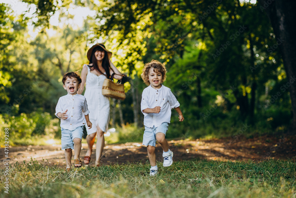 Fototapeta premium Mother with two sons in park having fun