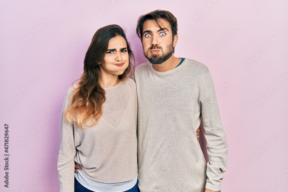 Young hispanic couple wearing casual clothes puffing cheeks with funny face. mouth inflated with air, crazy expression. Young hispanic couple wearing casual clothes puffing cheeks with funny face. mouth inflated with air, crazy expression.