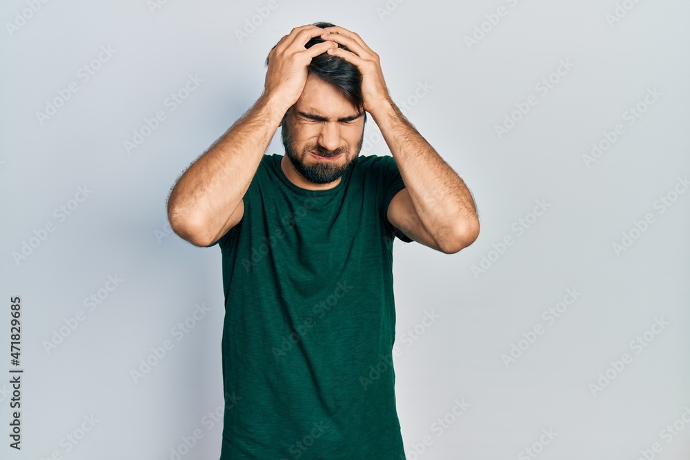 Young hispanic man wearing casual white tshirt suffering from headache desperate and stressed because pain and migraine. hands on head. Young hispanic man wearing casual white tshirt suffering from headache desperate and stressed because pain and migraine. hands on head.