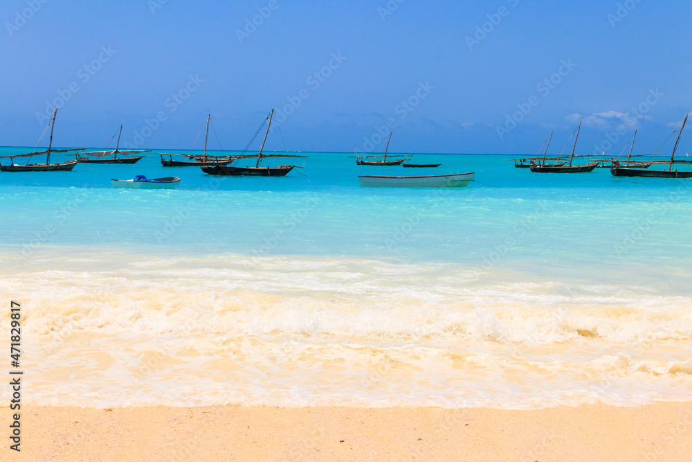 View of tropical sandy Nungwi beach and traditional wooden dhow boats in the Indian ocean on Zanzibar, Tanzania View of tropical sandy Nungwi beach and traditional wooden dhow boats in the Indian ocean on Zanzibar, Tanzania