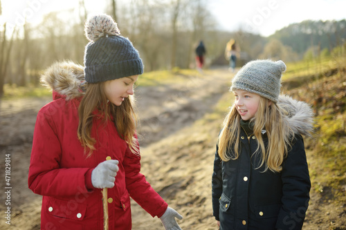 Two cute young sisters having fun during forest hike on beautiful early spring day. Active family leisure with kids.