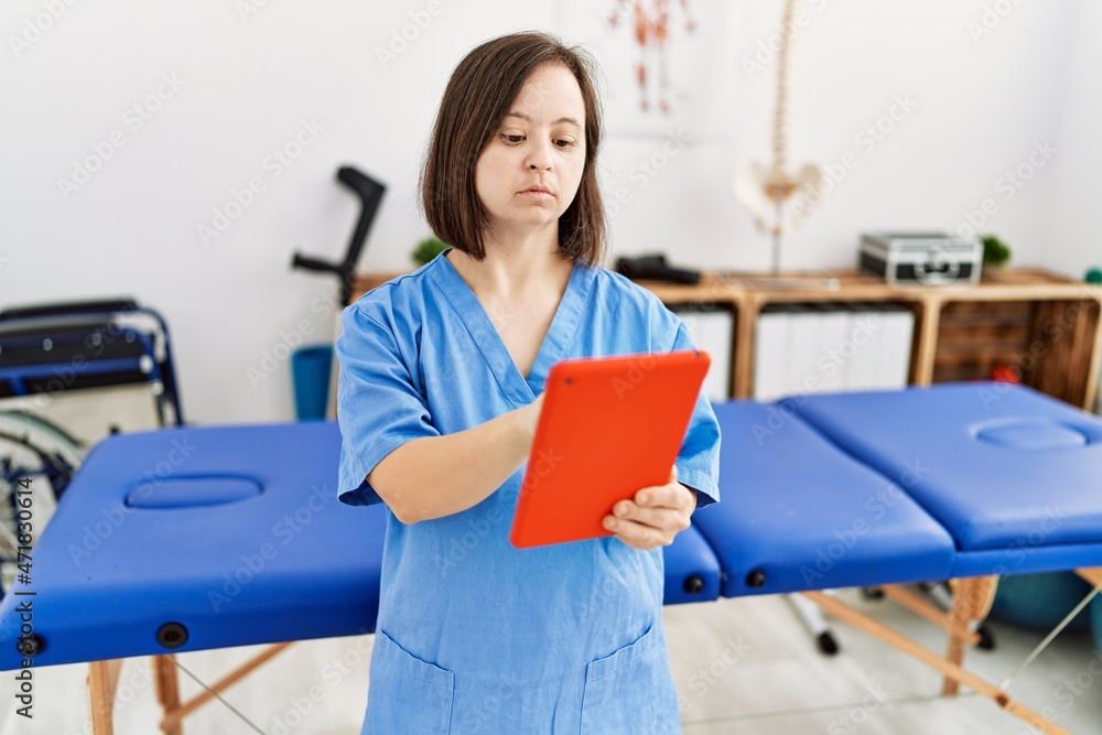 Brunette woman with down syndrome working using tablet at physiotherapy clinic Brunette woman with down syndrome working using tablet at physiotherapy clinic