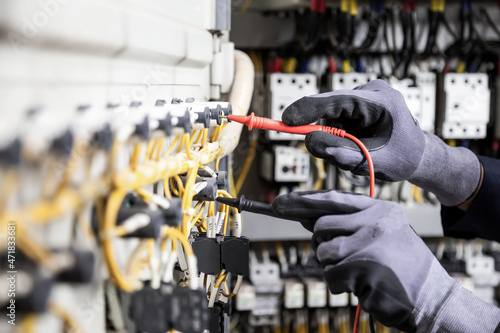 Electrician engineer tests electrical installations and wires on relay protection system. Adjustment of scheme of automation and control of electrical equipment.