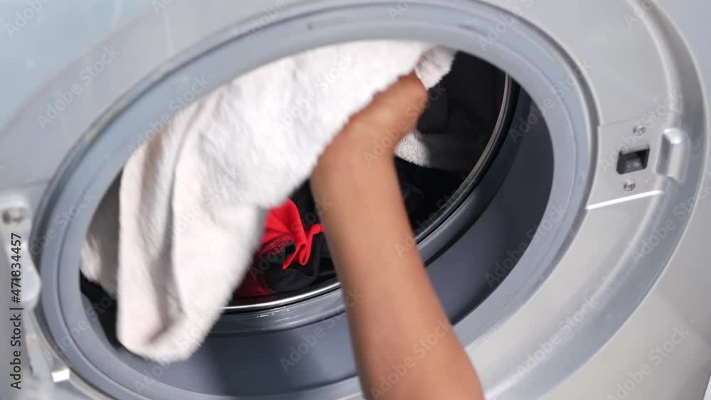 putting towel and cloths in a washing machine. putting towel and cloths in a washing machine.